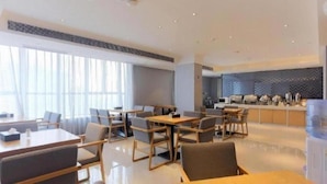 En modern hotellobby med en matplats, en receptionsdisk och ett kök i bakgrunden.