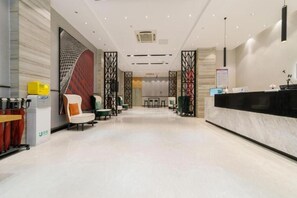 A hotel lobby with a reception desk, seating area, and a large abstract wall art piece. - Borrman Hotel (Jieyang)