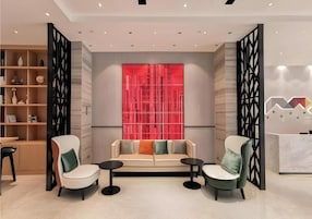 Un interior moderno con un sofá, dos sillones, una mesita y un panel decorativo rojo.
