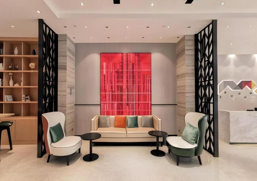 A modern interior with a sofa, two chairs, a small table, and a decorative red panel.
