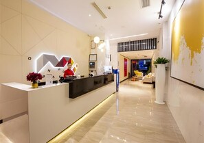 Un espace d’accueil moderne, comprenant un comptoir de réception, un écran numérique et un coin salon avec un canapé et des fauteuils.