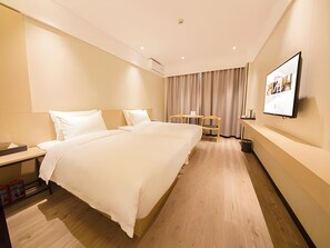 Une chambre d’hôtel avec un grand lit, des tables de chevet, un bureau, une chaise, un téléviseur fixé au mur et un rideau.