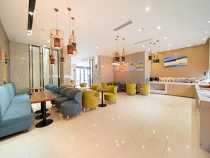 Un intérieur moderne comprenant des espaces de détente, des tables et un coin cuisine.