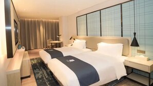 Habitación de hotel con dos camas, un escritorio, una silla, un televisor y un ventanal con vistas.