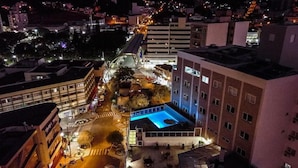 Un edificio alto con piscina en la azotea y zona de estar al aire libre.