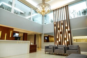 A modern hotel lobby with a reception desk, seating area, and large windows. - Hotel Alvorada - Concordia (Concordia)