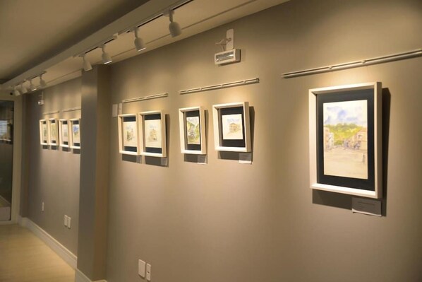 A hallway with framed artworks on the walls, a ceiling light fixture, and a wall-mounted air conditioning unit. - Hotel Alvorada - Concordia (Concordia)