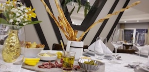 A dining table set with a clear glass, a bowl of olives, a glass of yellow liquid, and a vase with white flowers. - Hotel Alvorada - Concordia (Concordia)