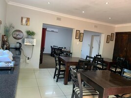 Un comedor con una mesa y sillas de madera, una estación de café y cuadros en las paredes.
