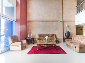 A spacious lobby with a red carpet, leather sofas, and a decorative table with a vase. - Capital O Hotel Herederos, Piedras Negras (Piedras Negras)
