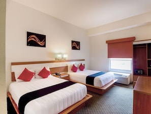A hotel room with two beds, a desk, a wardrobe, and artwork on the walls. - Capital O Hotel Herederos, Piedras Negras (Piedras Negras)