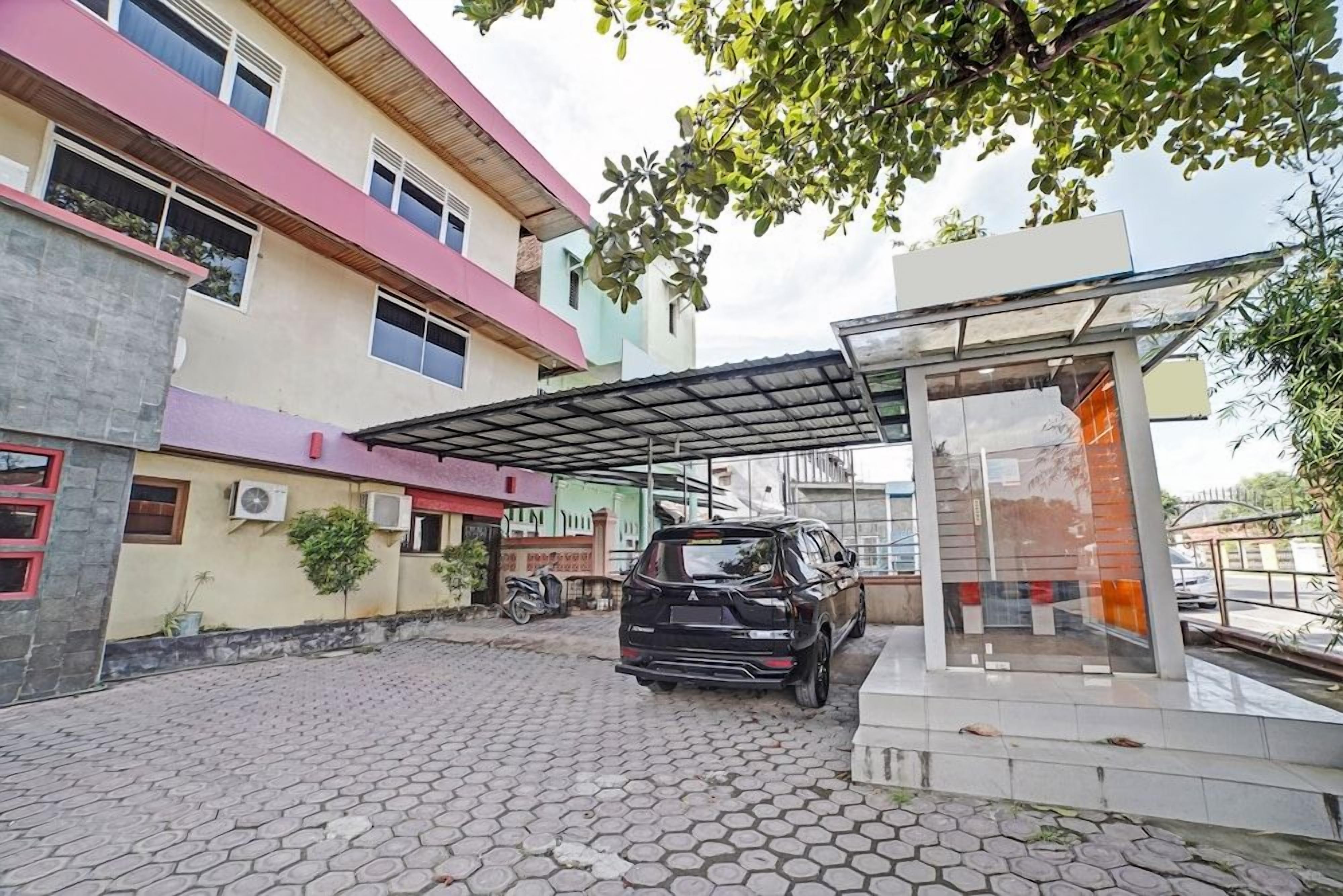 A black SUV parked in a covered parking area with a building in the background.