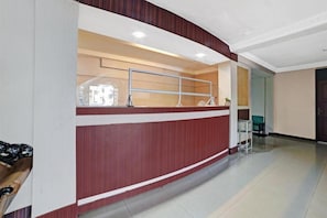 A reception area with a curved reception desk, a metal railing, and a chair.