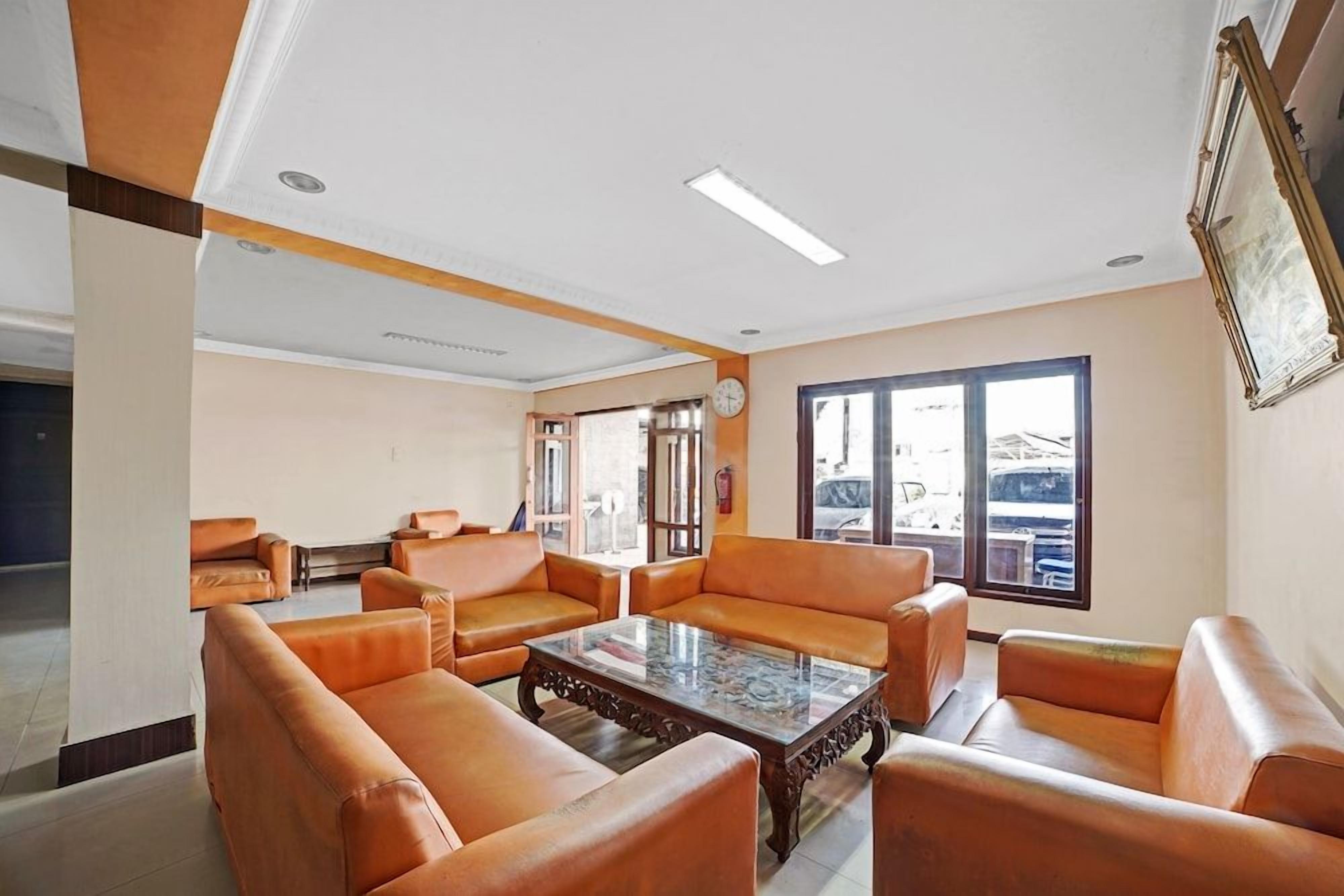 A spacious room with leather sofas, a glass coffee table, and large windows offering a view.
