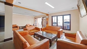 Ein Zimmer mit Ledersofas, die um einen Couchtisch angeordnet sind, einer Uhr an der Wand und einem Fenster mit Blick nach draußen.