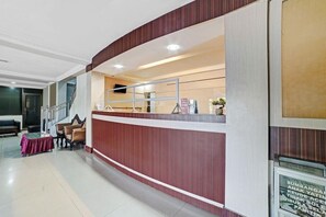 A reception area with a counter, seating, and a staircase. - OYO 90487 Wisma Kuta Karang Baru (Lhokseumawe)