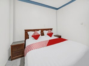 A bedroom with a bed, two nightstands, and a wooden headboard.