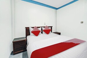 A bedroom with a bed, two nightstands, a red and white bedspread, and a blue accent wall. - OYO 90487 Wisma Kuta Karang Baru (Lhokseumawe)