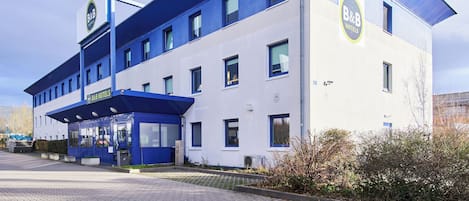 A B&B hotel with a blue and white facade, a covered entrance, and a clear sky.