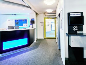 A reception area with a reception desk, a computer monitor, and a sign for the Internet- terminal. - Ibis Budget Hannover Messe (Laatzen)