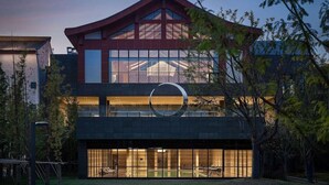 Un edificio moderno con una linea di tetto particolare e un ampio logo circolare.
