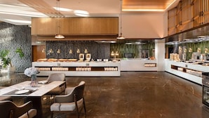 Una cucina moderna con isola centrale, illuminazione a sospensione e schienale in pietra.