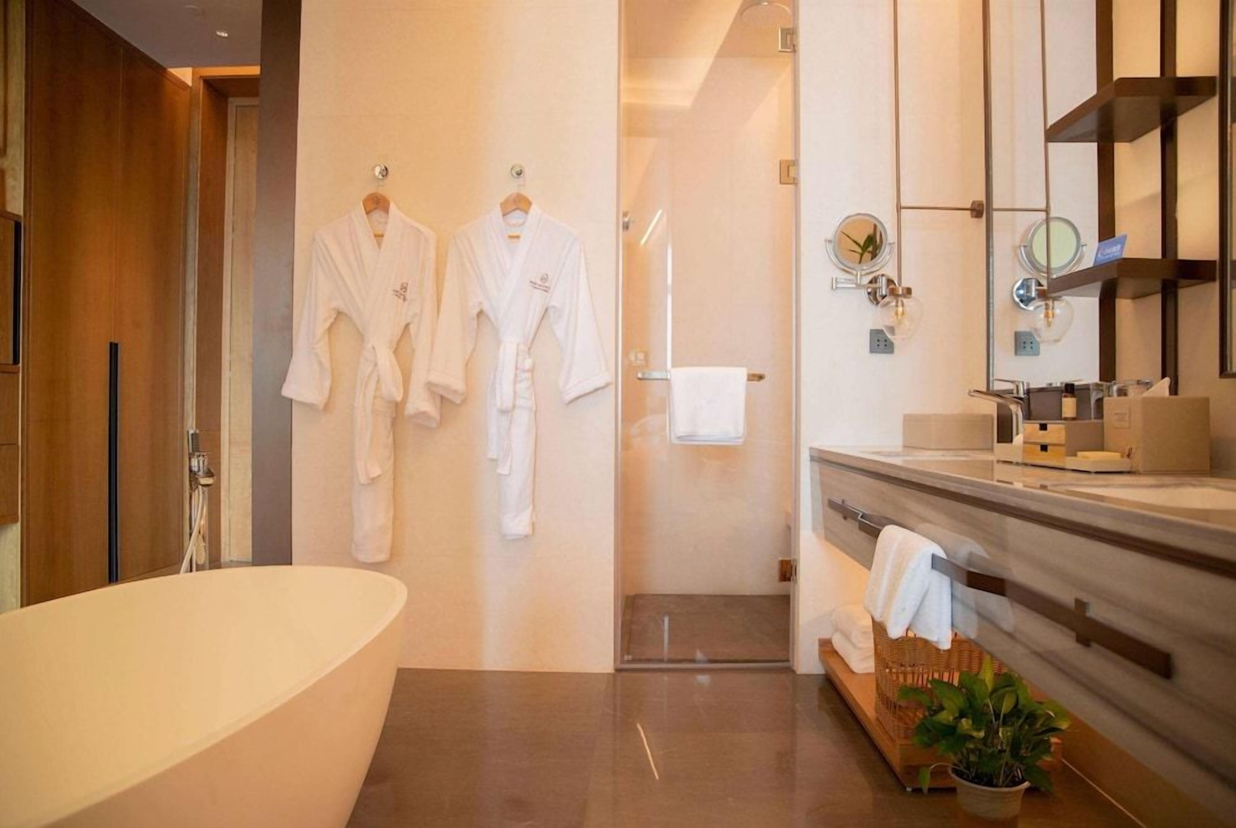 Une salle de bain moderne avec une baignoire sur pieds, une douche à parois de verre et un meuble-lavabo doté d’un miroir et d’un porte-serviettes.