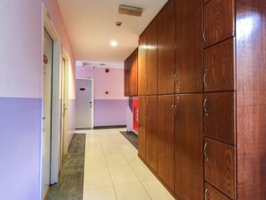 A hallway with a wooden wardrobe, a door, and a tiled floor.
