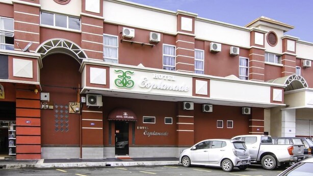 A hotel with a prominent entrance, multiple air conditioning units, and a parking area with several cars. - OYO 43930 Hotel Esplanade (Sandakan)