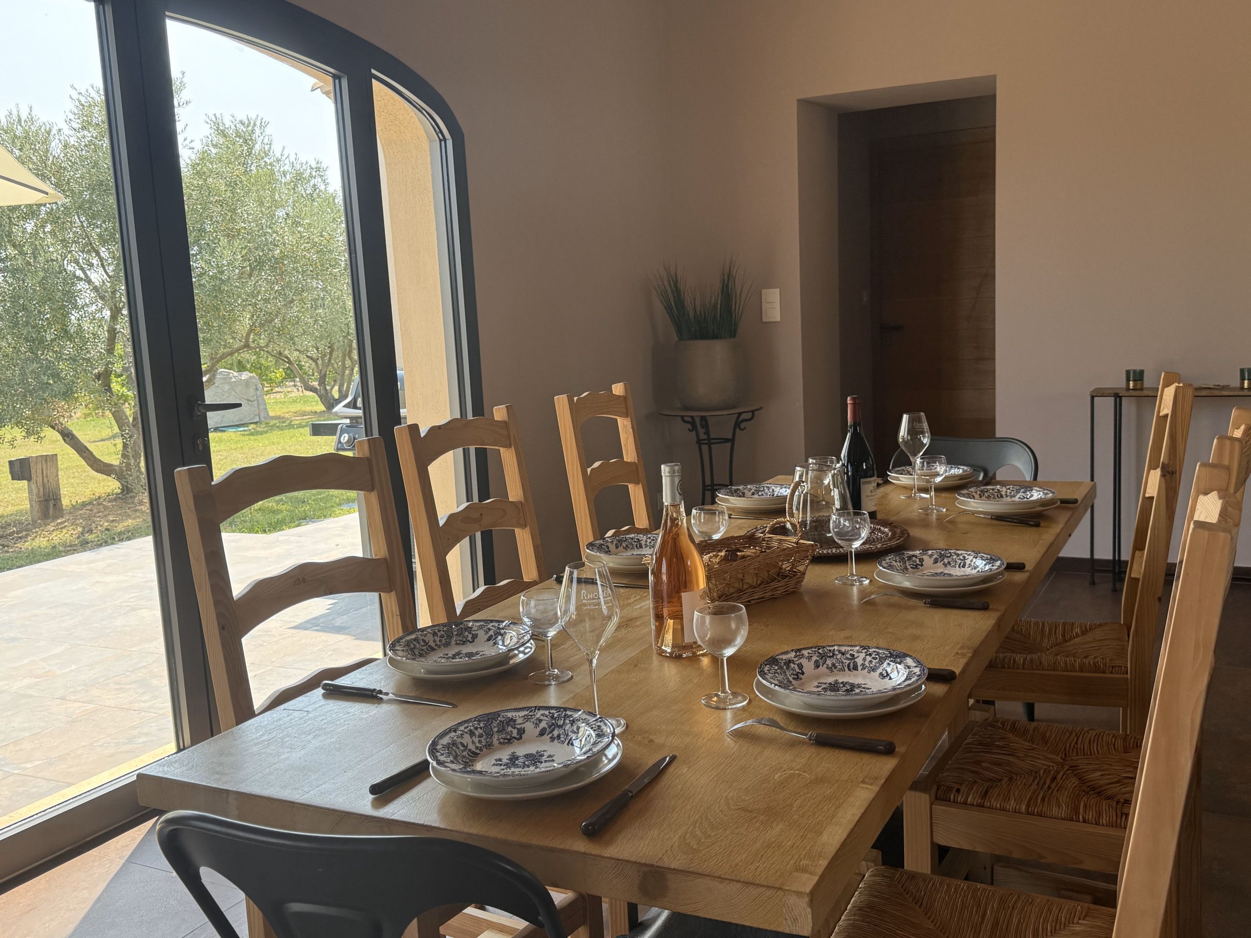 Une table à manger dressée avec des assiettes, des verres et des couverts, entourée de chaises.