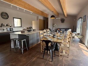Een moderne keuken met een centraal eiland, houten stoelen en een eettafel gedekt voor een maaltijd.