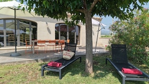 An outdoor seating area with tables and chairs, a tree, and a lounge chair with a towel. - 8-person Ventoux view villa in the heart of the vineyards (Caromb)