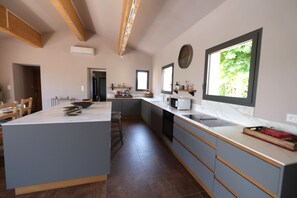A modern kitchen with a central island, built-in appliances, and a large window providing natural light. - 8-person Ventoux view villa in the heart of the vineyards (Caromb)
