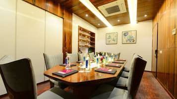 A conference room with a wooden table, grey chairs, water bottles, and a bookshelf.