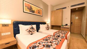 A hotel room with two beds, a headboard, bedside tables, a painting, and a wardrobe.