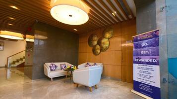 A lobby with a reception desk, a sofa, a coffee table, and a decorative wall.