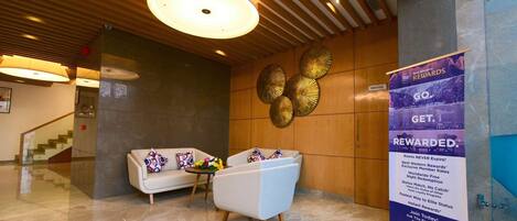 A lobby with a reception desk, a sofa, a coffee table, and a decorative wall.