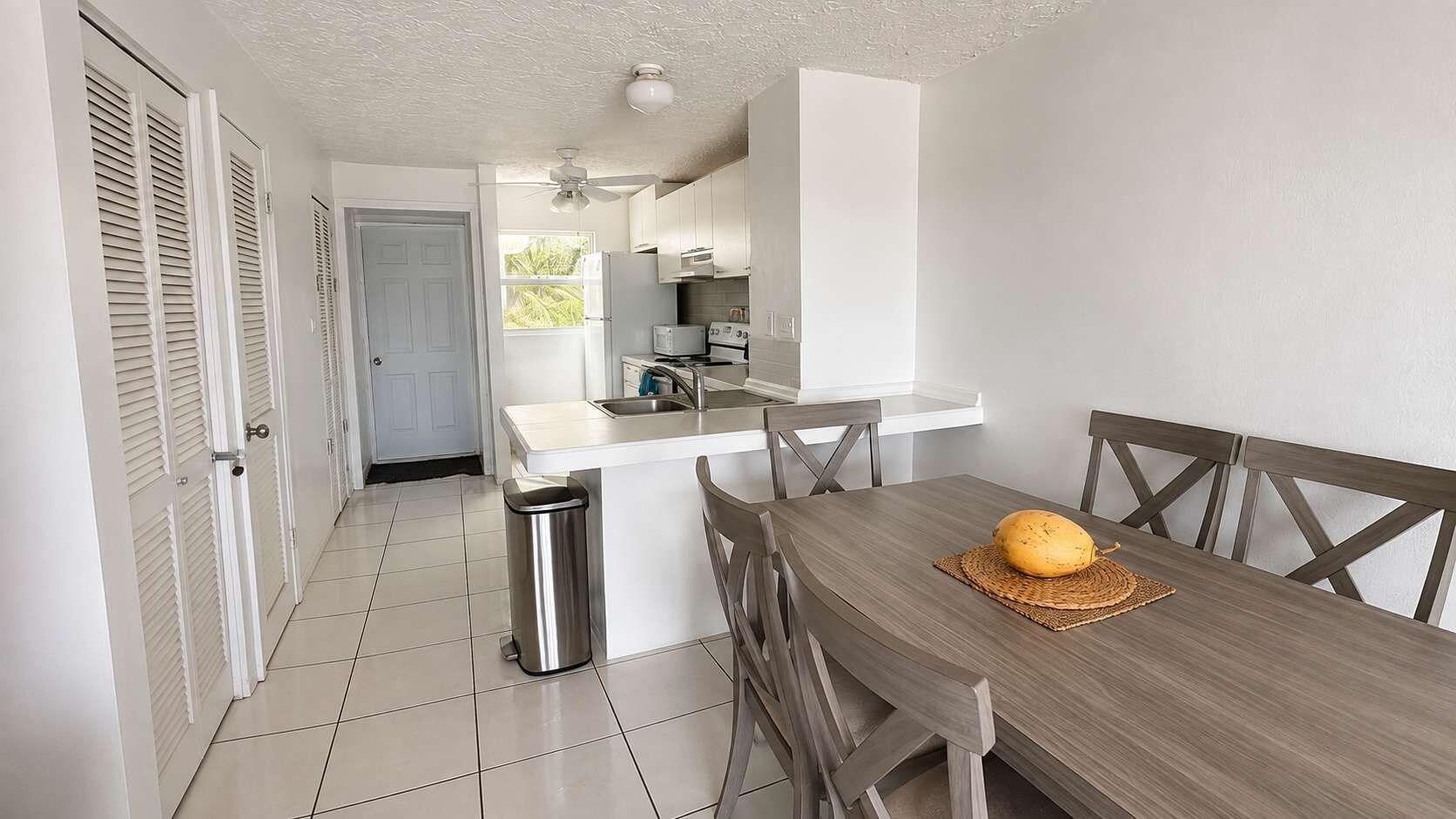 A kitchen with a central island, a dining table with chairs, and a trash bin.