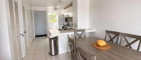 A kitchen with a central island, a dining table with chairs, and a trash bin.