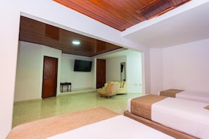 A hotel room with a wooden ceiling, a flat-screen TV mounted on the wall, a sofa, and two beds with beige bedding. - Hotel Med 94 Barranquilla (Barranquilla)