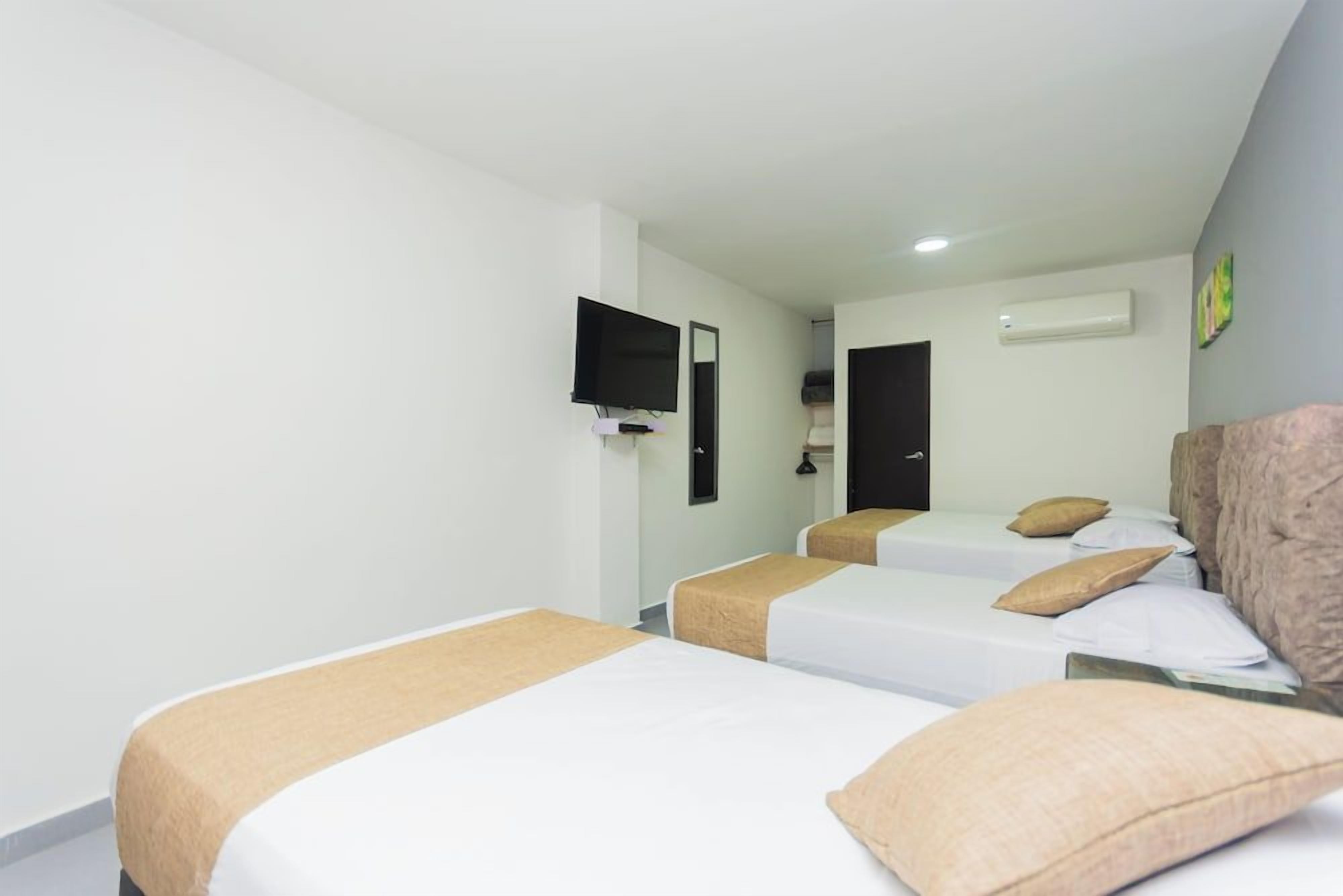 A hotel room with two beds, a television, and an air conditioning unit.