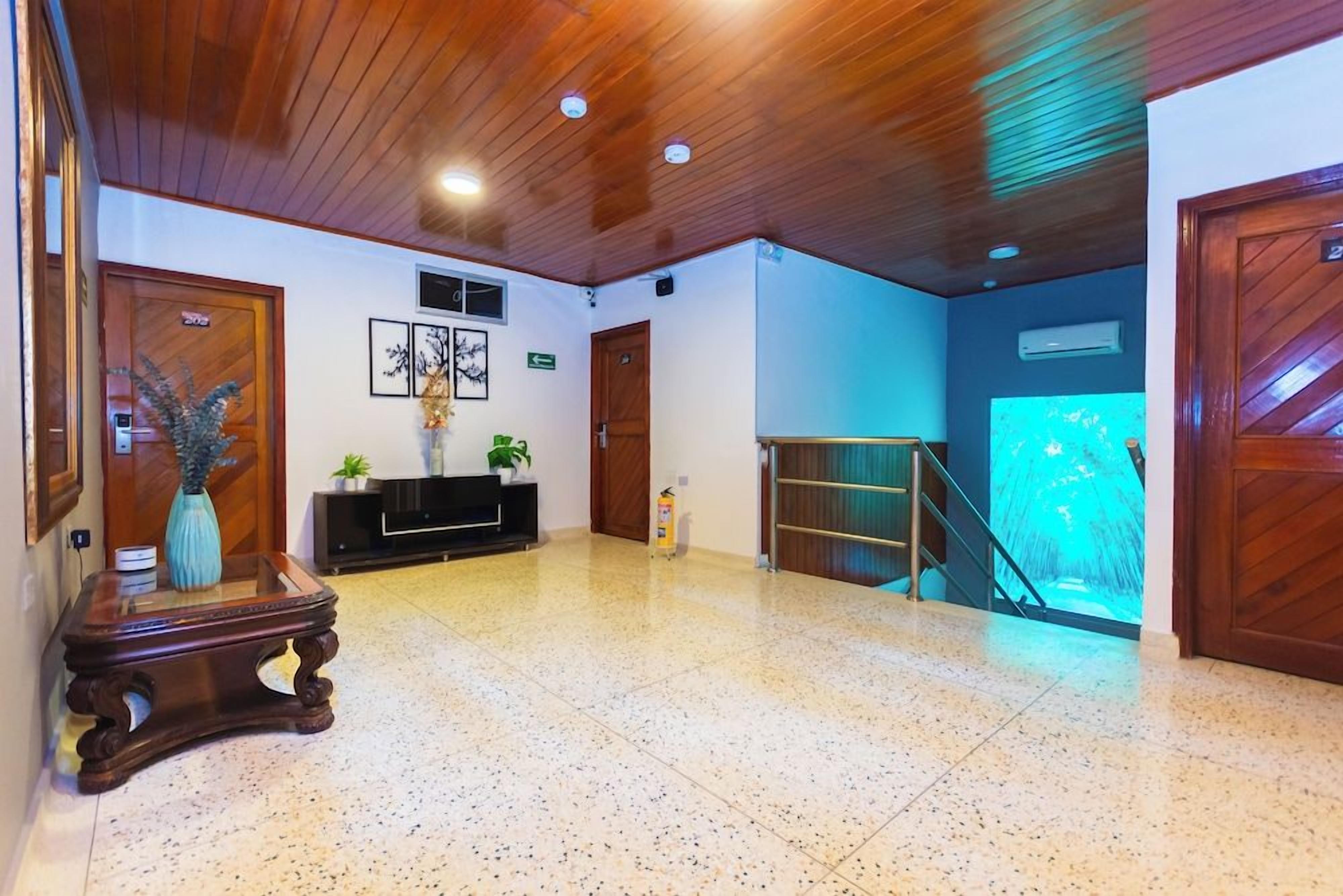 Eine geräumige Lobby mit Holzboden, einem Glastisch, einer Pflanze und einer Treppe.