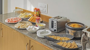 A kitchen counter with various breakfast items including eggs, bread, and a toaster. - Treebo Trend Mall View (Gurugram)