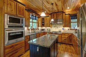 A kitchen with wooden cabinets, stainless steel appliances, granite countertops, and a central island.