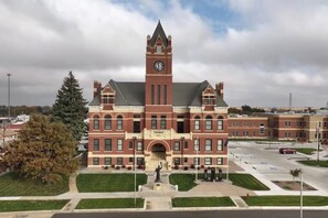 A large brick building with a clock tower, a central entrance, and a statue in front.