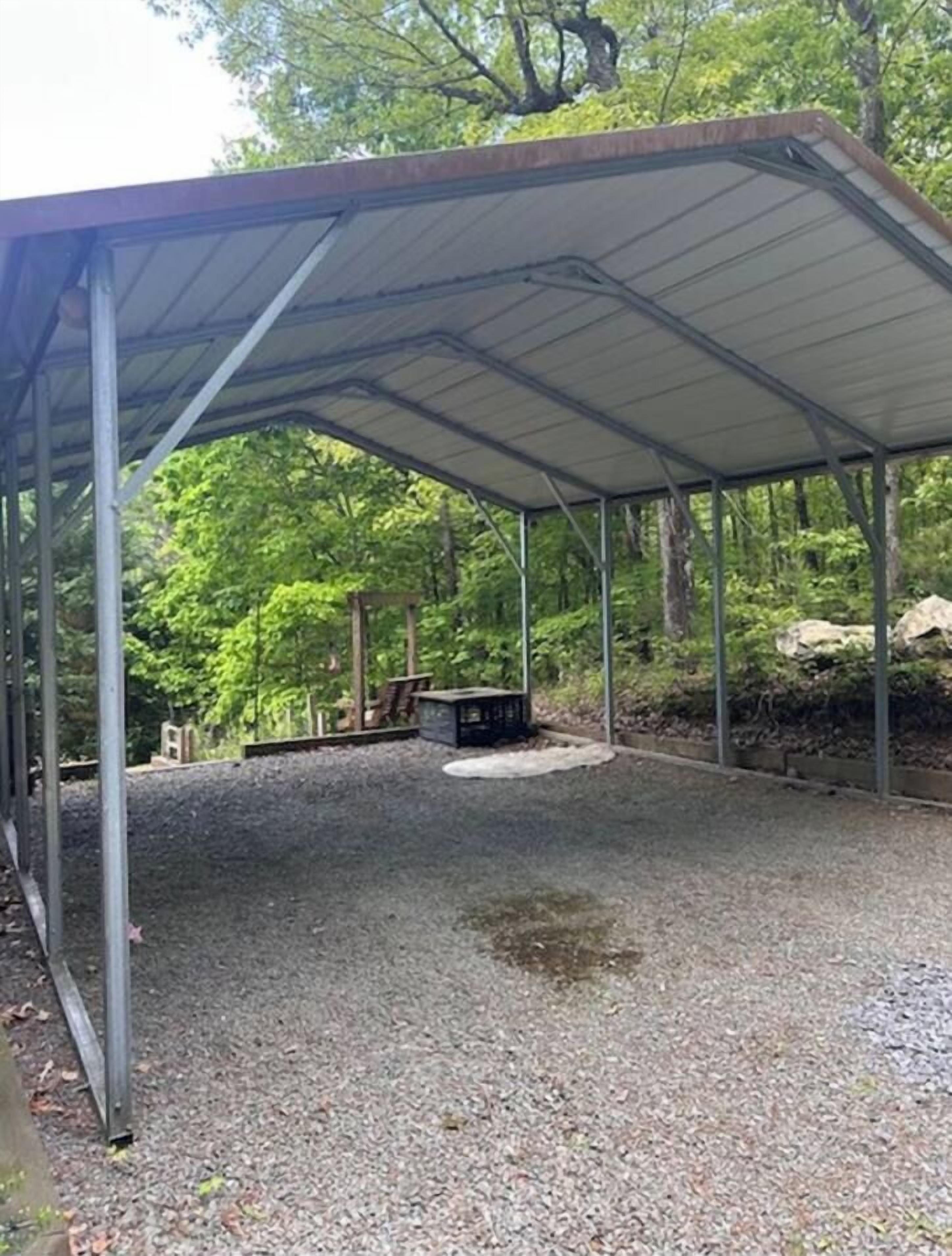Un espace extérieur abrité, doté d’un sol en gravier, d’un petit foyer et d’une structure métallique.