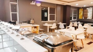 A modern restaurant with a long counter, white chairs, and a buffet area. - Ibis Hotel (Beijing)