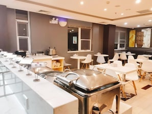 Un restaurant moderne avec un long comptoir, des chaises blanches et un espace buffet.