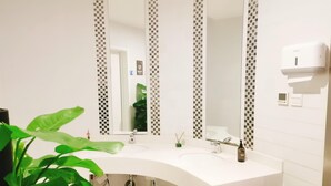 A bathroom with a white sink, a mirror, and a hand dryer. - Ibis Hotel (Beijing)