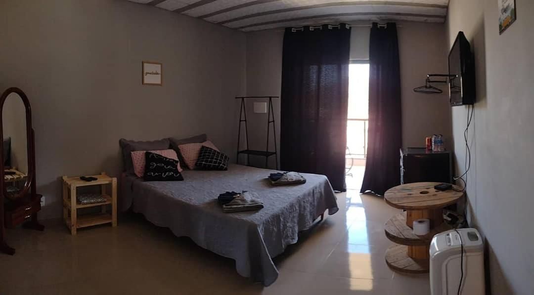 Quarto com cama, mesa de cabeceira e uma pequena mesa com cadeira.